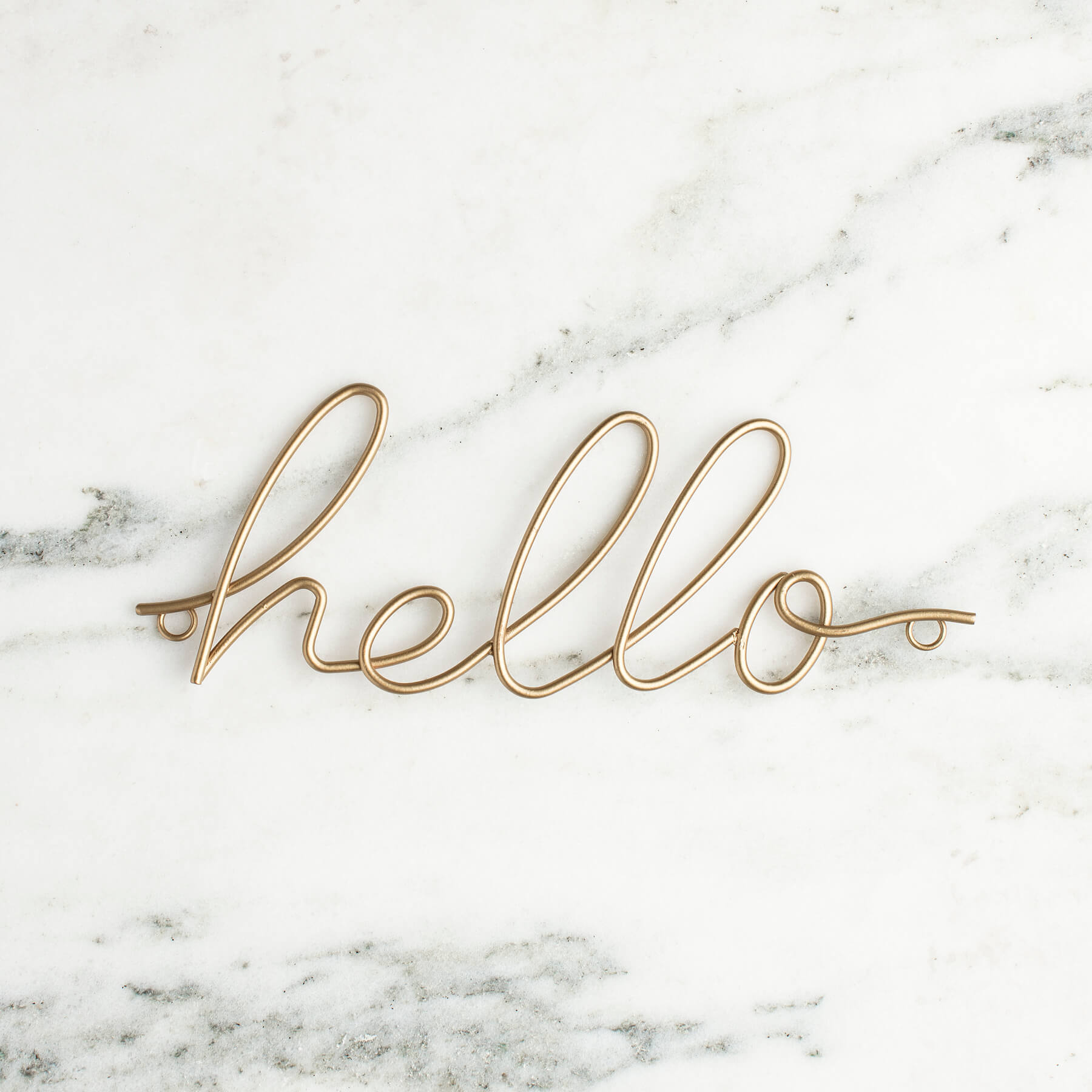 Gold cursive hello sign on white marble